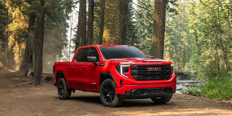 Red 2026 GMC Sierra 1500 truck on a forest trail