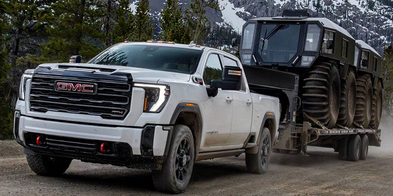2026 GMC Sierra 3500 HD towing heavy equipment on a trailer