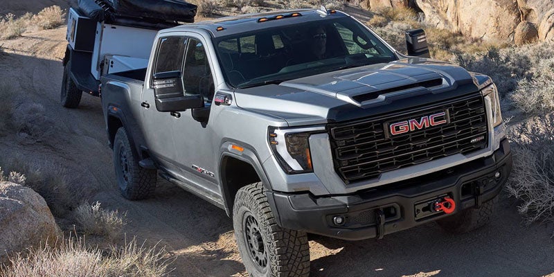 2026 GMC Sierra 3500 HD AT4 driving on a rugged off-road trail